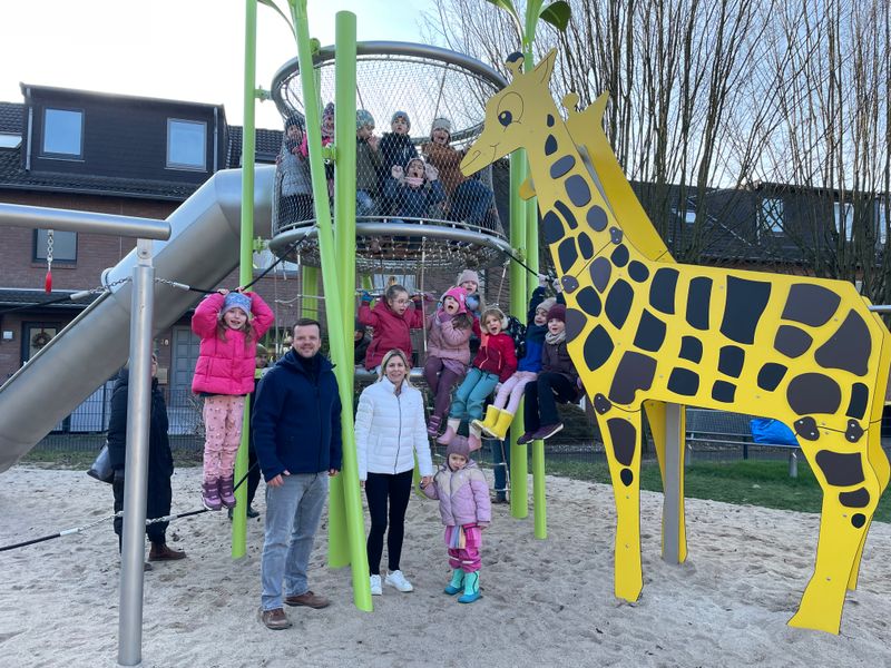 Eine Gruppe Menschen steht an einem Giraffenspielgerät.